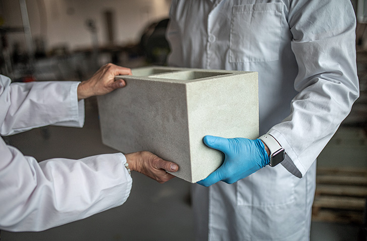A Prometheus concrete block being handed off in the lab.